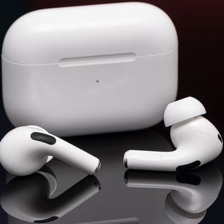 White wireless earbuds with charging case on a reflective surface